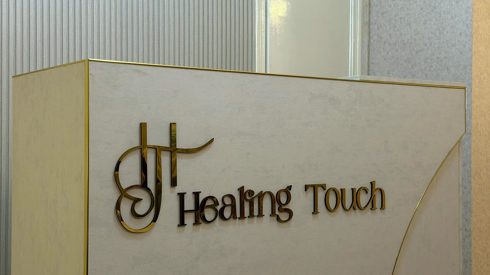 The Healing Touch reception desk, the clinic name in gold on marble
